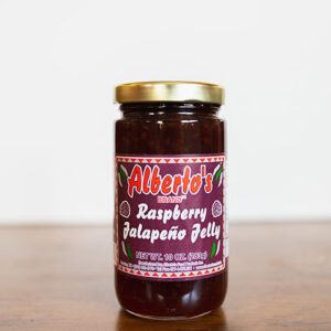 A jar of raspberry jalapeno jelly on top of a table.