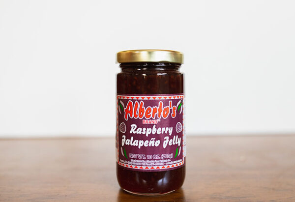A jar of raspberry jalapeno jelly on top of a table.