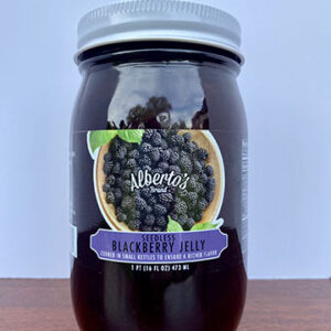 A jar of blackberry jelly sitting on top of a table.