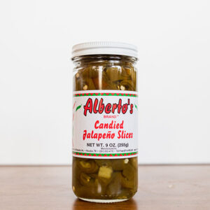 A jar of condided jalapeno slices on top of a table.