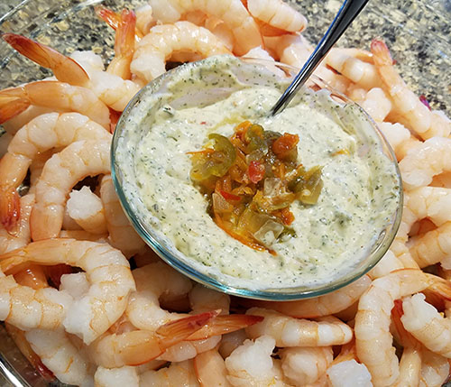 A bowl of dip on top of some shrimp.