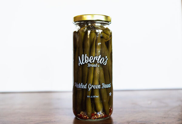 A jar of pickled green beans on top of a table.