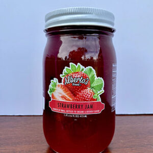 A jar of strawberry jam on top of a table.